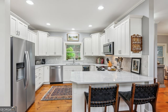61 Deer Run Rdg, Big Canoe, GA 30143 - kitchen featuring stainless steel appliances, ornamental molding, a sink, a peninsula, and light wood finished floors