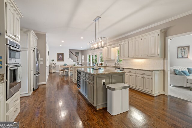 420 Windswept Ct, Roswell, GA 30075 - kitchen featuring appliances with stainless steel finishes, a chandelier, dark wood-style floors, decorative backsplash, and light stone countertops