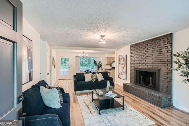 9 Windsor Way, Newnan, GA 30263 - living area featuring light wood-type flooring, a textured ceiling, a chandelier, and a brick fireplace