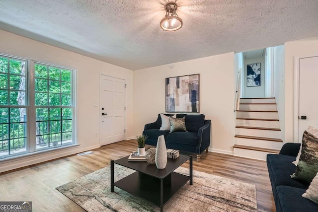 9 Windsor Way, Newnan, GA 30263 - living area featuring a textured ceiling, healthy amount of natural light, stairway, wood finished floors, and baseboards
