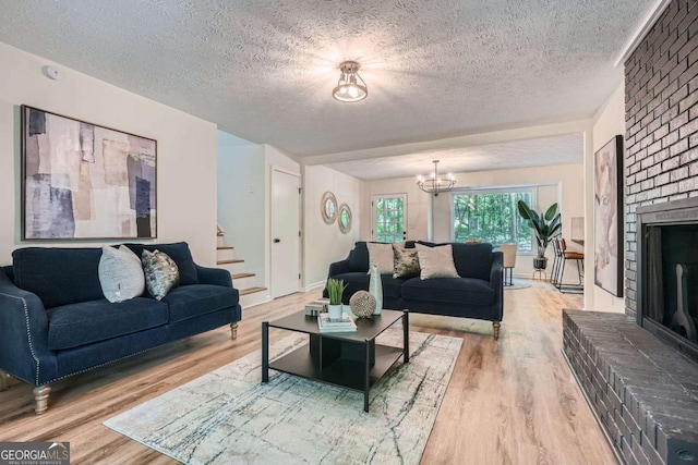 9 Windsor Way, Newnan, GA 30263 - living area with a textured ceiling, stairs, wood finished floors, a chandelier, and a brick fireplace