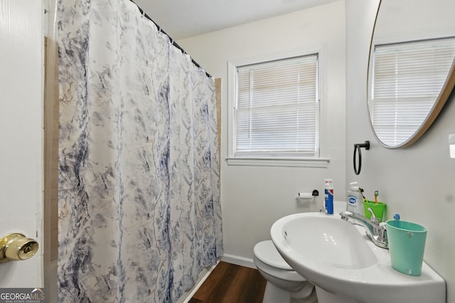 full bathroom with wood finished floors, a shower with curtain, a sink, baseboards, and toilet