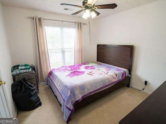 bedroom featuring light carpet and a ceiling fan