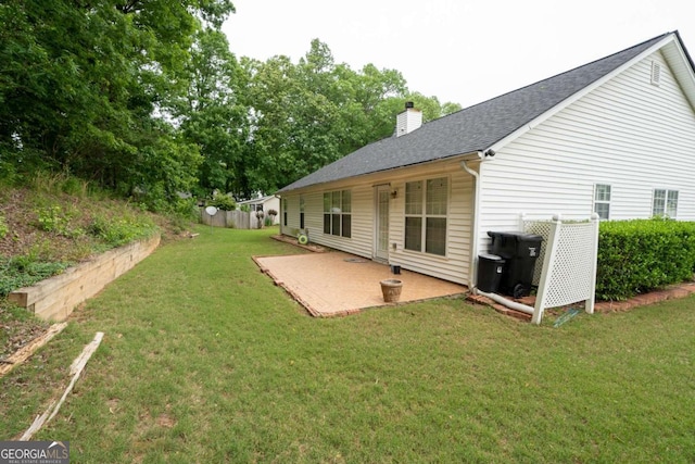 rear view of house with a chimney, a patio area, and roof with shingles