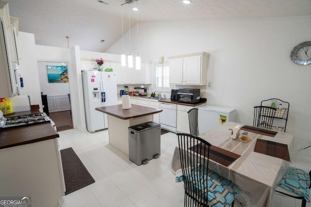 kitchen with white appliances, a sink, a center island, white cabinets, and pendant lighting
