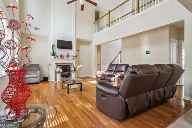 1520 Ethans Way, Mcdonough, GA 30252 - living area with a ceiling fan, a high ceiling, wood finished floors, a fireplace with flush hearth, and baseboards