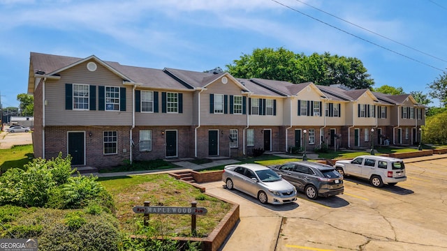 view of property with brick siding, uncovered parking, and a residential view