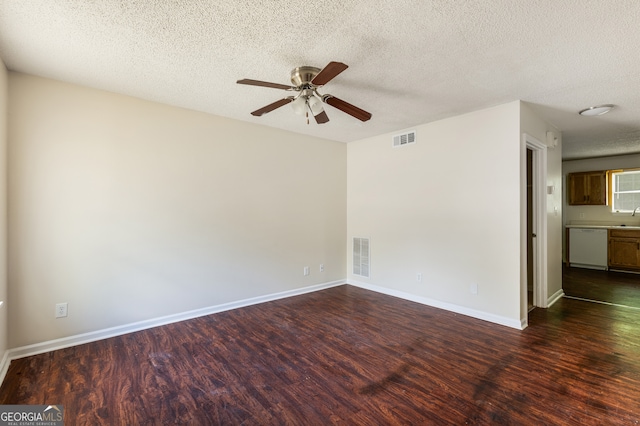 empty room with dark wood finished floors, a ceiling fan, a textured ceiling, baseboards, and a sink