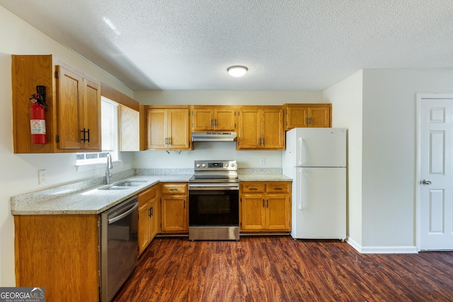 kitchen featuring stainless steel appliances, a sink, under cabinet range hood, dark wood finished floors, and a textured ceiling