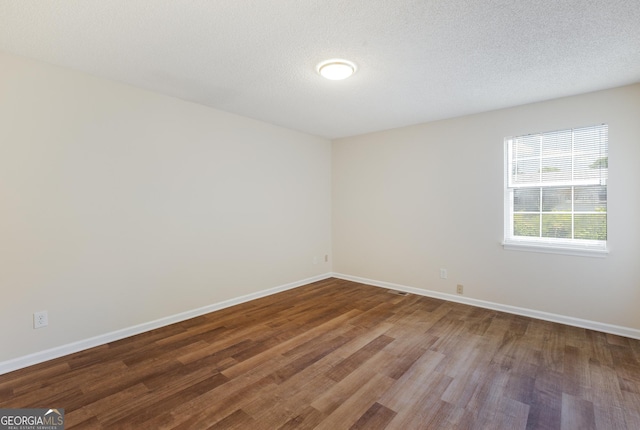 spare room featuring wood finished floors, baseboards, and a textured ceiling