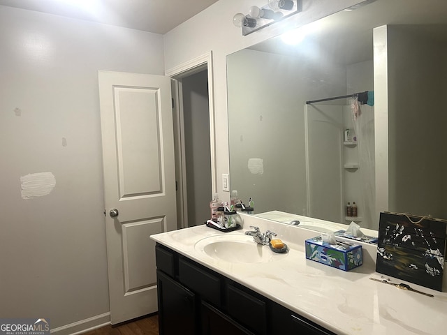 full bathroom featuring vanity, a shower, and wood finished floors
