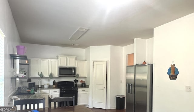 kitchen with stainless steel appliances, dark wood-style flooring, white cabinetry, and dark countertops