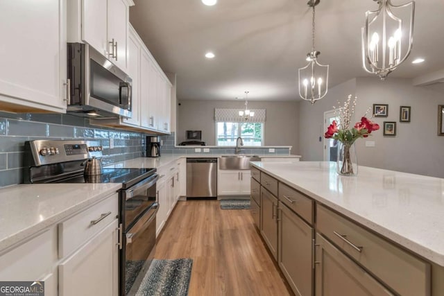592 Eagles Nest Cir, Auburn, GA 30011 - kitchen featuring stainless steel appliances, a chandelier, a sink, backsplash, and white cabinets