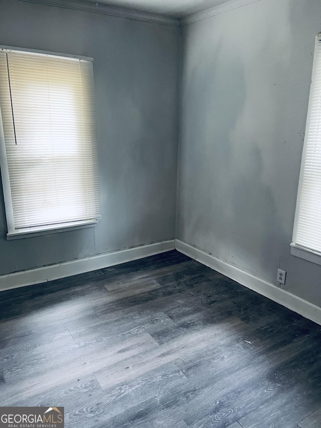 unfurnished room featuring wood finished floors, crown molding, and baseboards