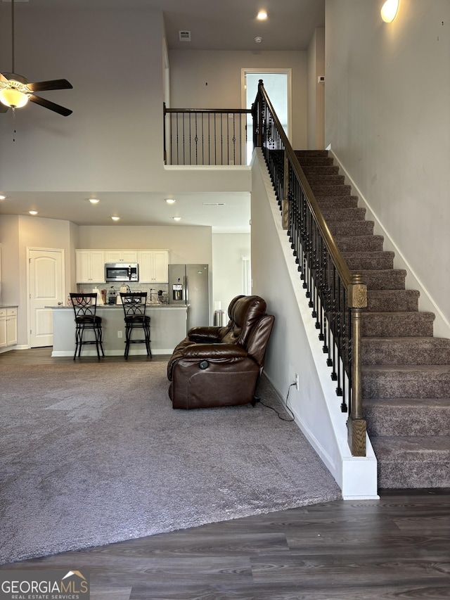 457 Panhandle Pl, Hampton, GA 30228 - living area with baseboards, stairs, ceiling fan, a high ceiling, and dark colored carpet
