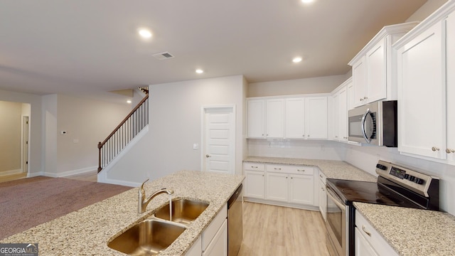 kitchen featuring stainless steel appliances, a sink, decorative backsplash, white cabinets, and recessed lighting
