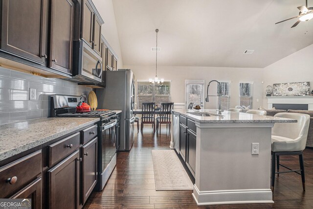3415 Linstead Ct, Loganville, GA 30052 - kitchen featuring appliances with stainless steel finishes, a sink, dark brown cabinetry, a chandelier, and lofted ceiling