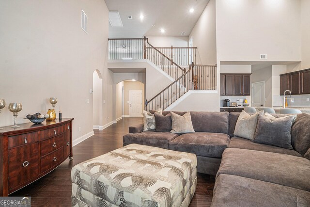 3415 Linstead Ct, Loganville, GA 30052 - living area featuring a high ceiling, arched walkways, stairs, dark wood-type flooring, and baseboards