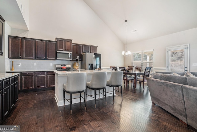 3415 Linstead Ct, Loganville, GA 30052 - kitchen featuring stainless steel appliances, high vaulted ceiling, open floor plan, a chandelier, and a center island with sink