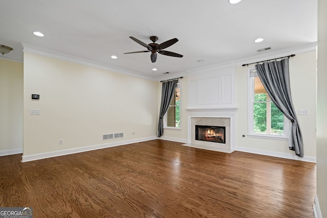 unfurnished living room featuring ceiling fan, crown molding, dark wood finished floors, a high end fireplace, and baseboards