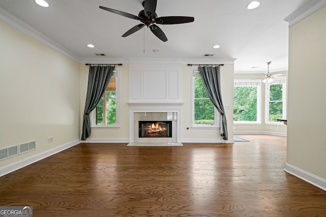 unfurnished living room with a ceiling fan, ornamental molding, baseboards, a premium fireplace, and healthy amount of natural light