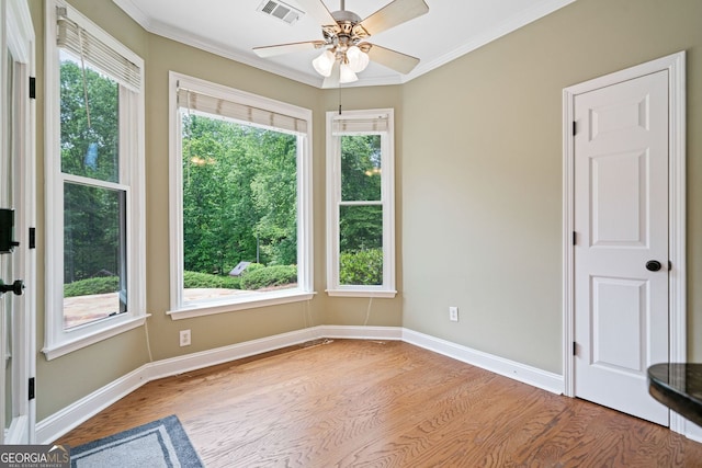 empty room with wood finished floors, ornamental molding, baseboards, and a ceiling fan