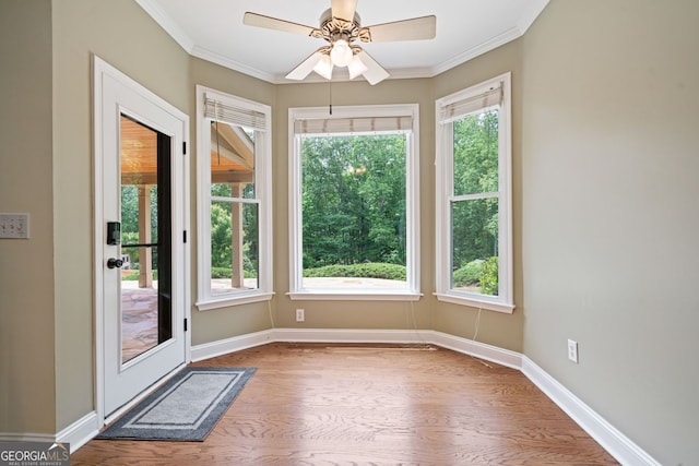 doorway with wood finished floors, ornamental molding, baseboards, and a ceiling fan