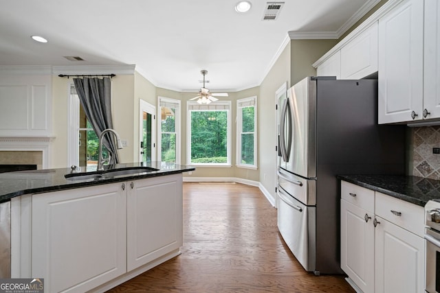 kitchen featuring a sink, white cabinets, decorative backsplash, wood finished floors, and a fireplace