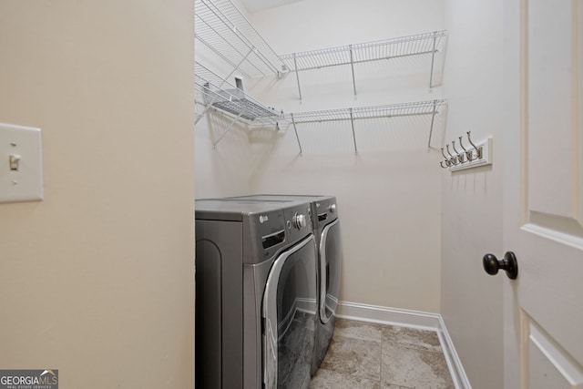 clothes washing area with washing machine and dryer and baseboards