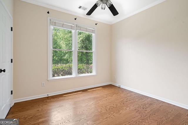 empty room with wood finished floors, ceiling fan, crown molding, and baseboards