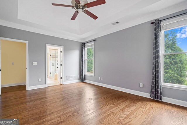spare room with wood finished floors, a tray ceiling, a ceiling fan, ornamental molding, and baseboards