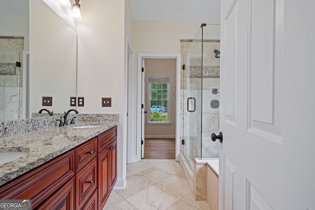 bathroom featuring a shower stall, double vanity, and baseboards