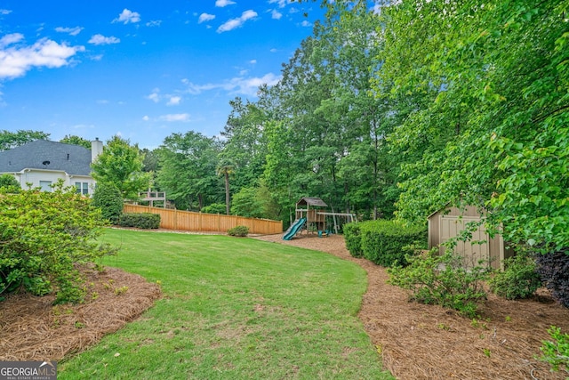view of yard featuring a playground, a storage unit, and an outbuilding