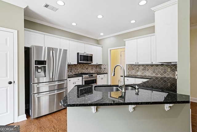 kitchen with appliances with stainless steel finishes, a sink, a peninsula, light wood-style floors, and recessed lighting