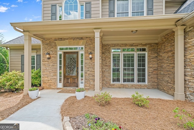 view of exterior entry featuring stone siding and covered porch