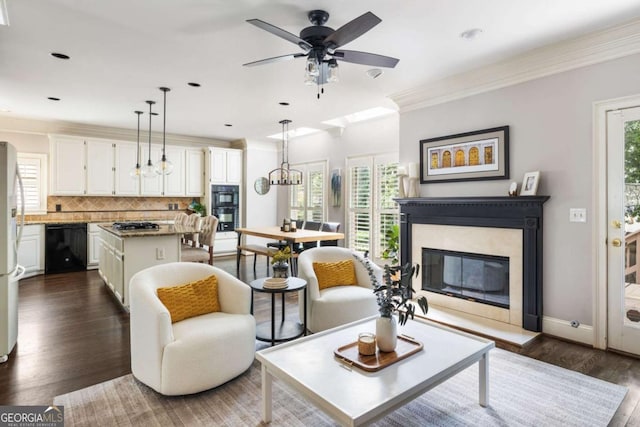 living area featuring dark wood-style floors, a high end fireplace, a ceiling fan, ornamental molding, and recessed lighting