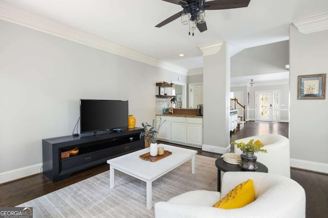 living area with stairway, baseboards, wood finished floors, a ceiling fan, and crown molding