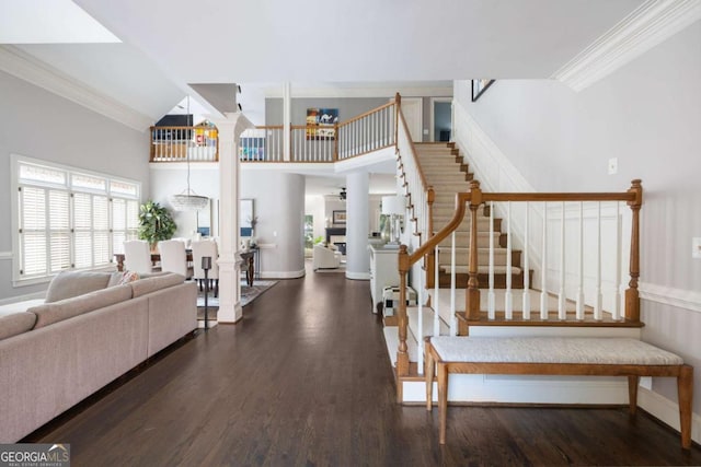 foyer featuring stairs, ornate columns, wood finished floors, crown molding, and baseboards