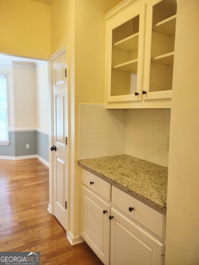 308 Bell Isle, Mcdonough, GA 30252 - kitchen with light wood-type flooring, backsplash, baseboards, glass insert cabinets, and light stone countertops
