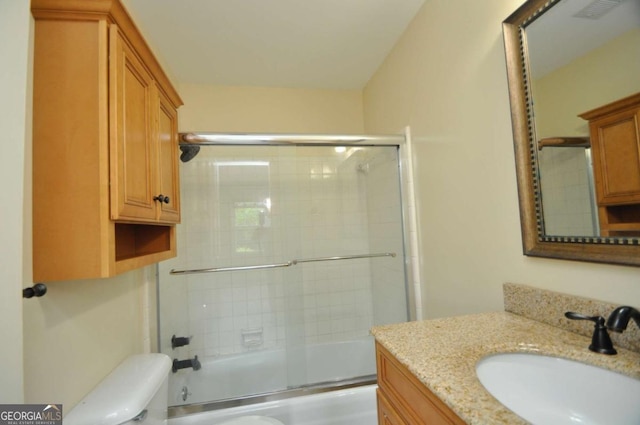 full bathroom featuring toilet, vanity, and shower / bath combination with glass door