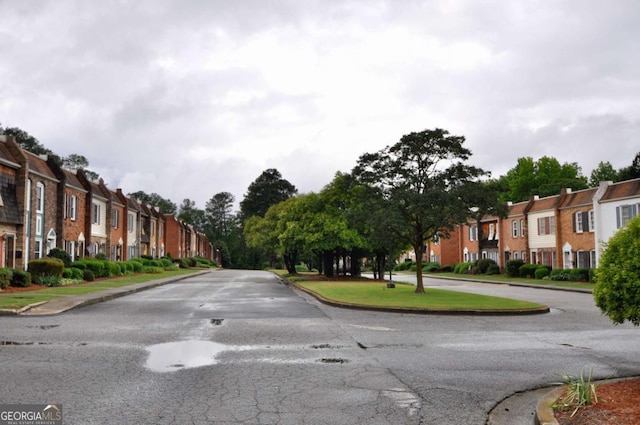 view of asphalt street with a residential view and curbs