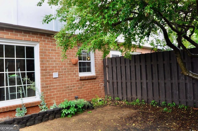 view of property exterior featuring brick siding and fence