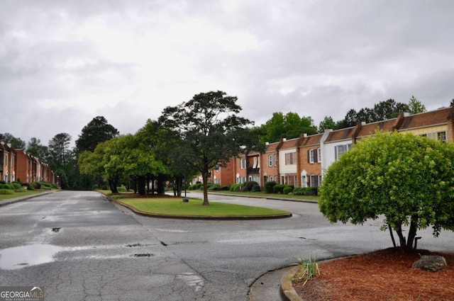 view of asphalt road featuring curbs and a residential view