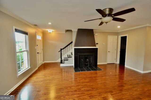 unfurnished living room with wood finished floors, baseboards, stairway, ornamental molding, and recessed lighting