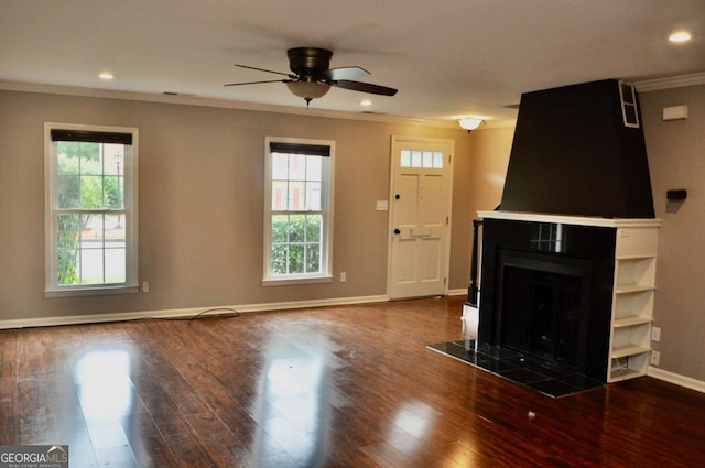 unfurnished living room with crown molding, baseboards, ceiling fan, wood finished floors, and a tile fireplace