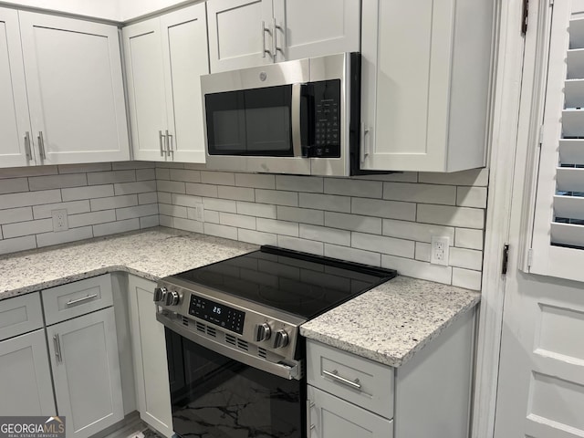 1858 Sahara Dr SE, Atlanta, GA 30316 - kitchen featuring appliances with stainless steel finishes, decorative backsplash, marble look tiles, light stone countertops, and white cabinets
