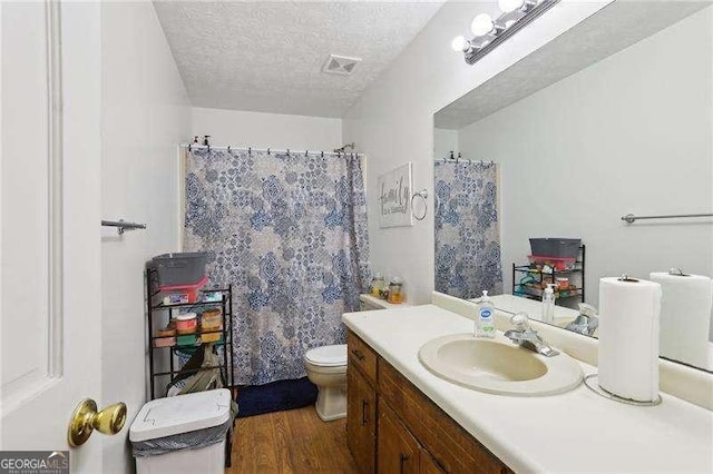 373 Dixie Ct, Lawrenceville, GA 30046 - bathroom featuring a textured ceiling, wood finished floors, toilet, vanity, and curtained shower