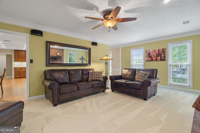 living area with light colored carpet, a ceiling fan, crown molding, baseboards, and a textured ceiling