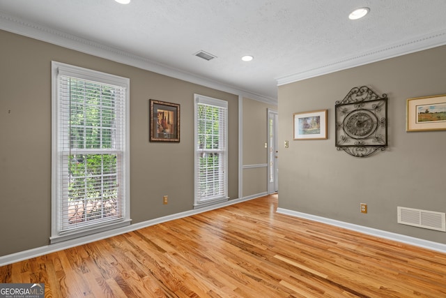 empty room with ornamental molding, baseboards, recessed lighting, a textured ceiling, and light wood-type flooring