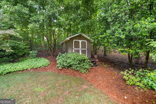 view of yard featuring a storage shed, an outdoor structure, and fence